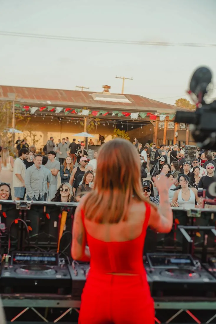 Woman in red watching the stage from the back of the crowd