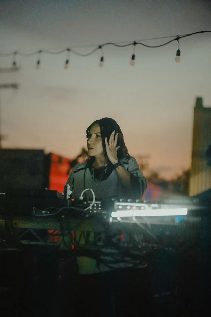 DJ at the decks at dusk under the string lights