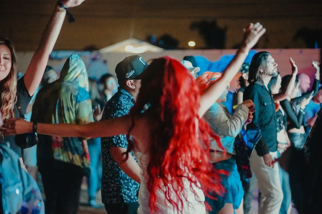 Crowd dancing with their arms up under blue light