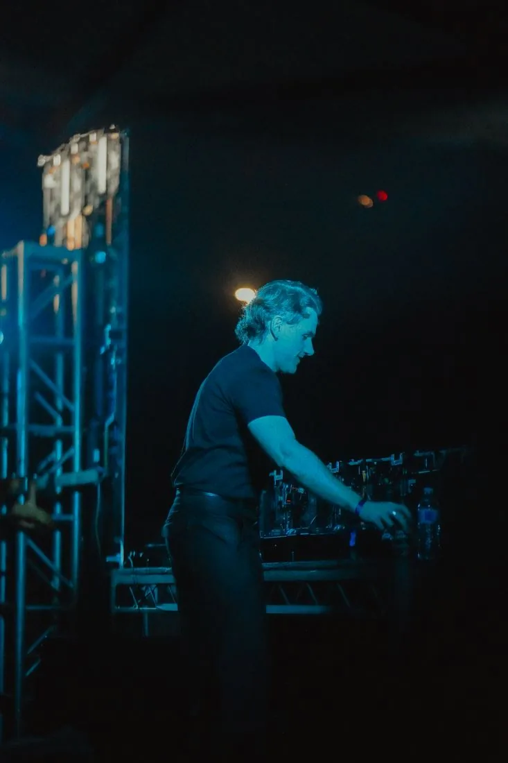 DJ alone at the decks under a cold blue wash