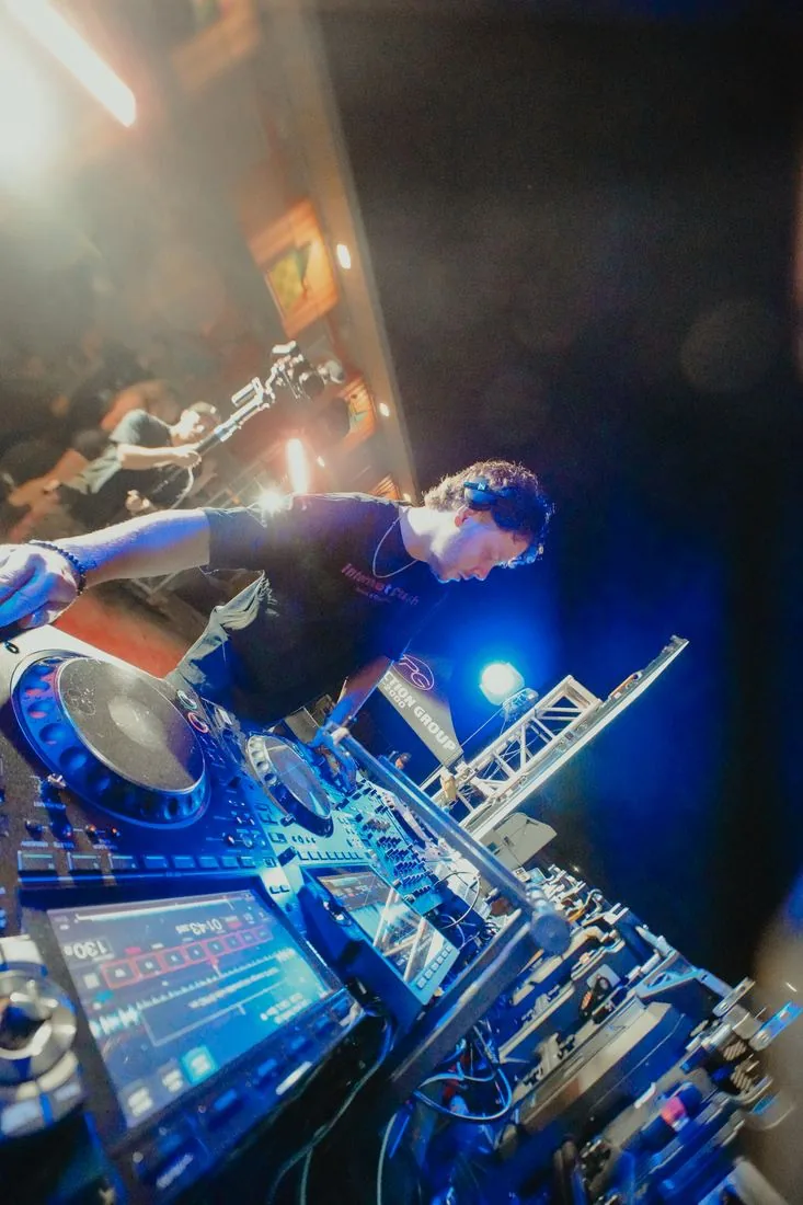 DJ at the decks in blue light with CO2 firing
