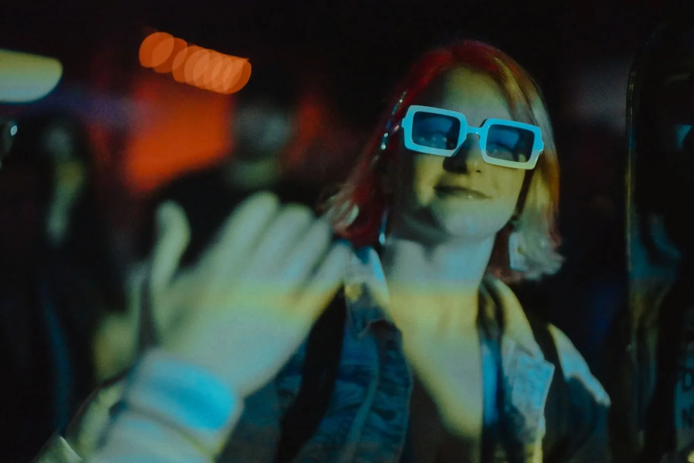 Person in white sunglasses at night under blue stage light