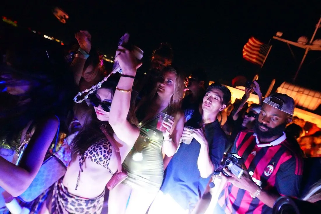 Night crowd dancing under pink and purple light