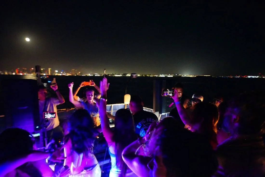 Crowd on the dark deck with the city lights and the moon behind