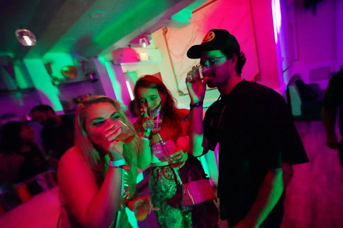 Group at the bar at night under pink and green light